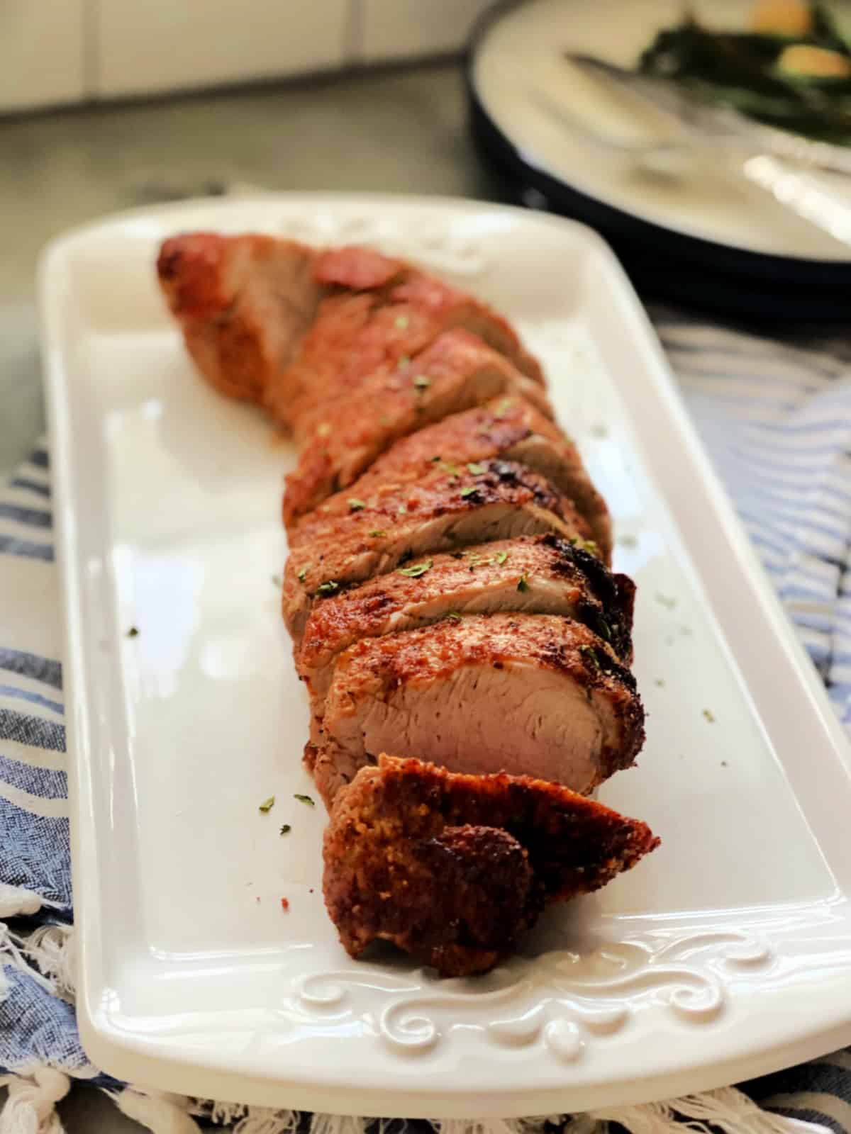 Sliced pork tenderloin on white serving dish