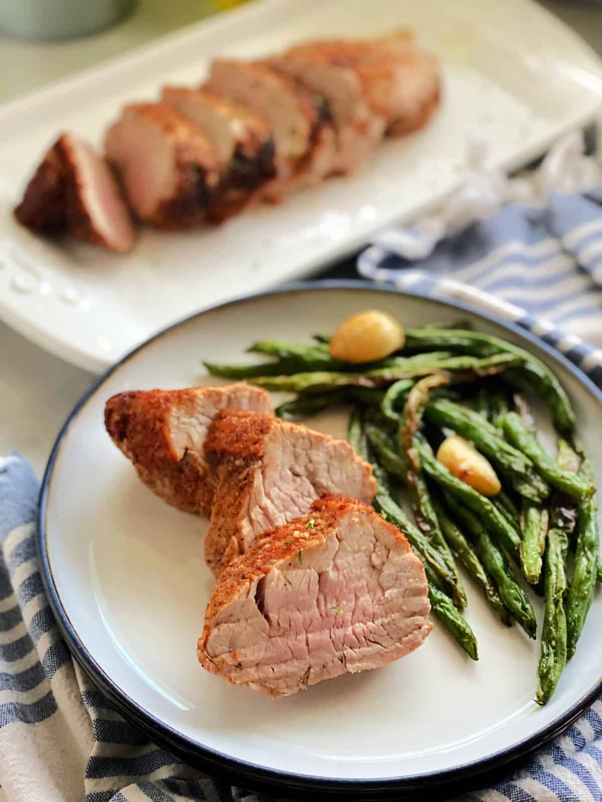 three slices of pork tenderloin with asparagus on white plate