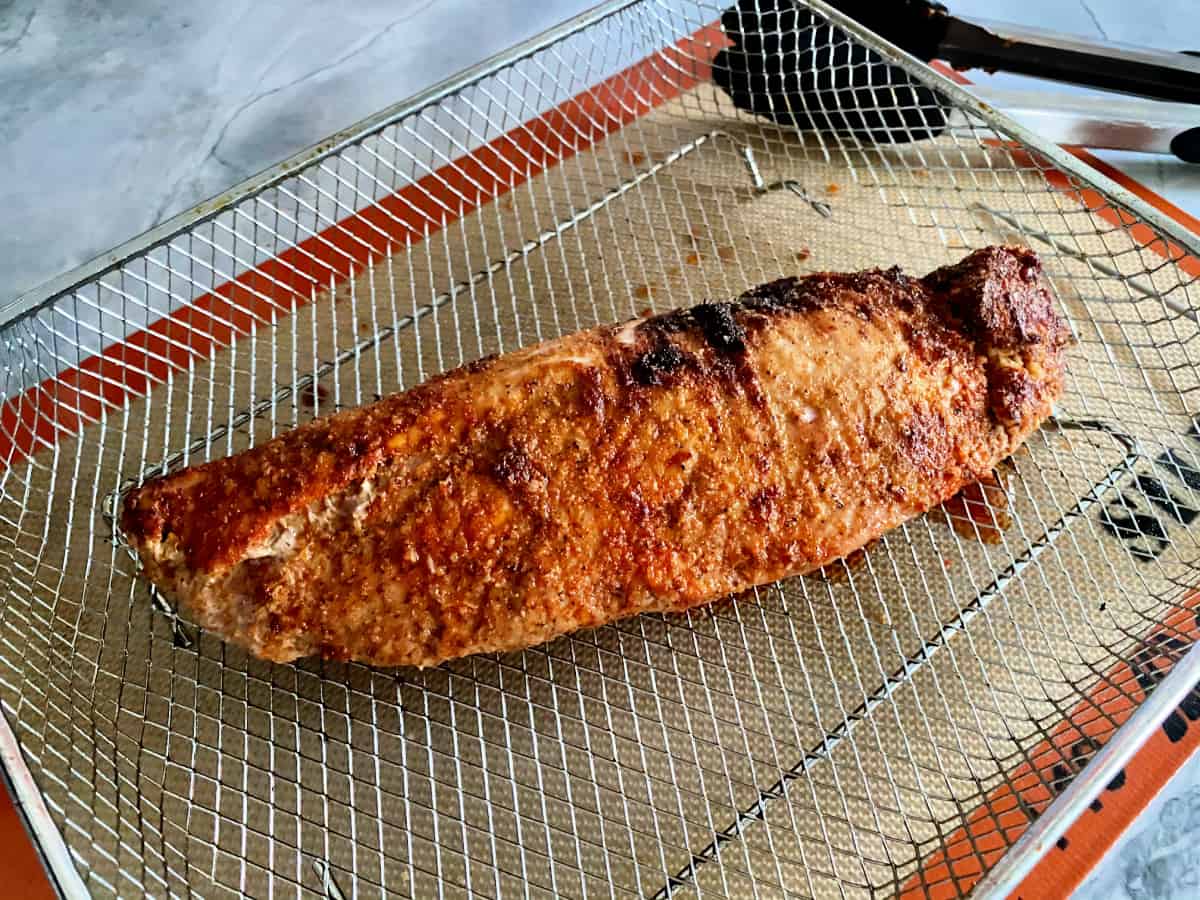 Air fried pork tenderloin resting on a wire rack