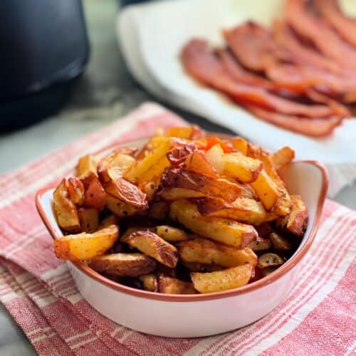 White dish with fried breakfast potatoes inside sitting on red and white towel