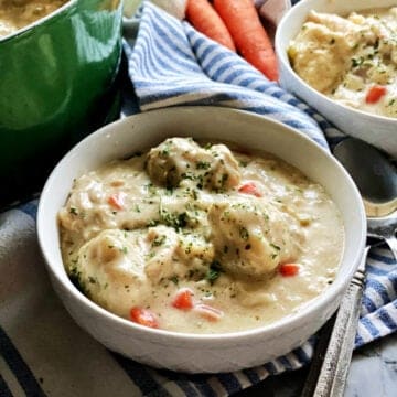 White bowl with dumplings and chicken in a bowl.