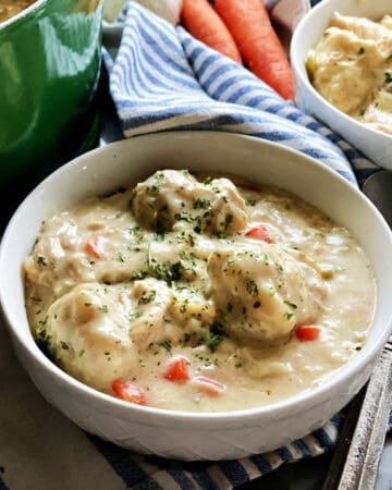White bowl with dumplings and chicken in a bowl.