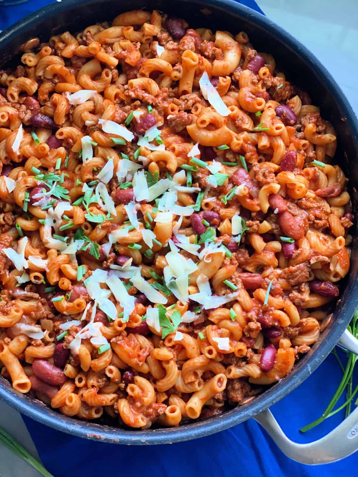 Chili pasta in large skillet topped with shredded cheese