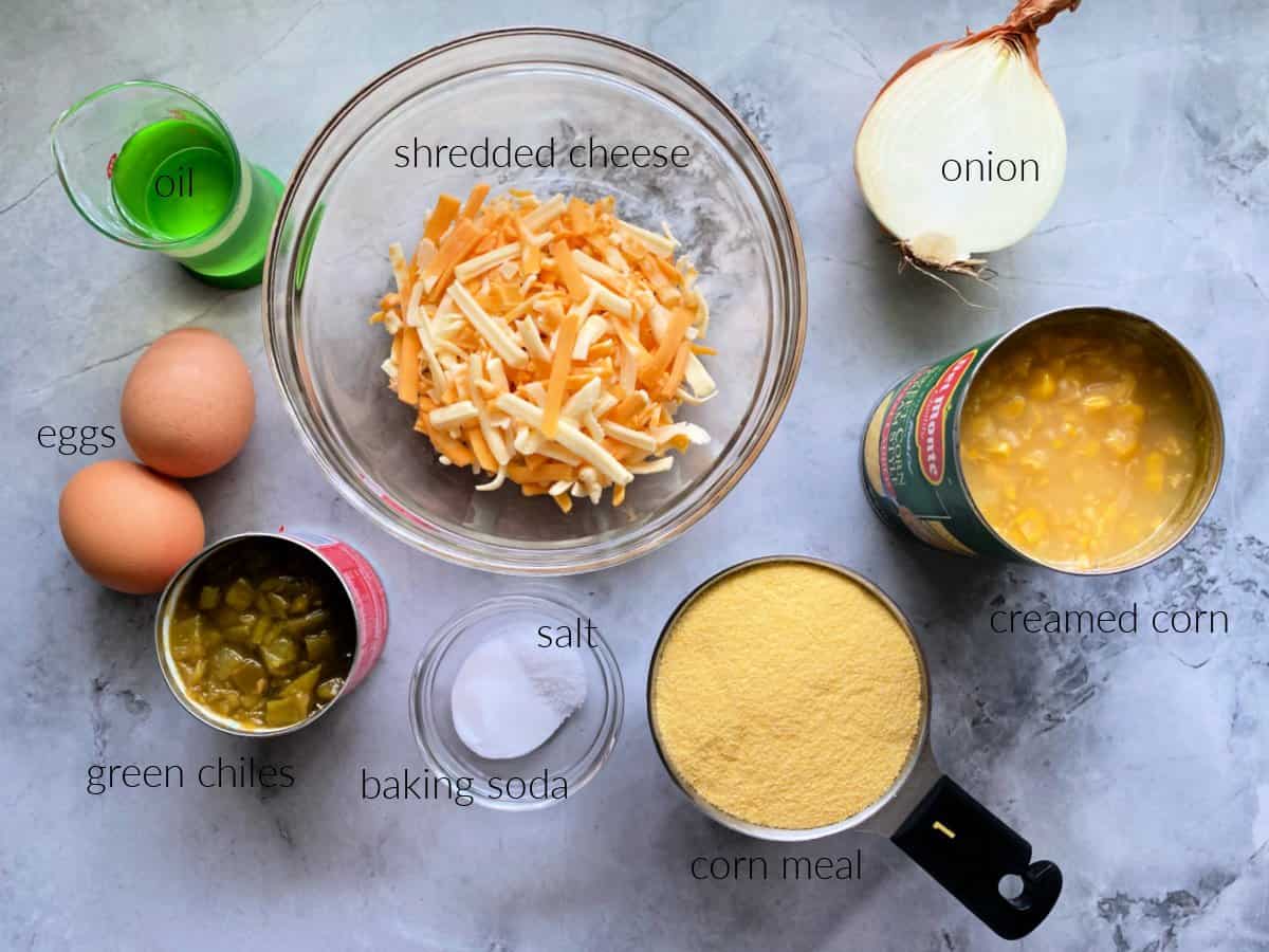 Cornbread ingredients: shredded cheese, onion, creamed corn, corn meal, baking soda & salt, green chiles, eggs, and oil