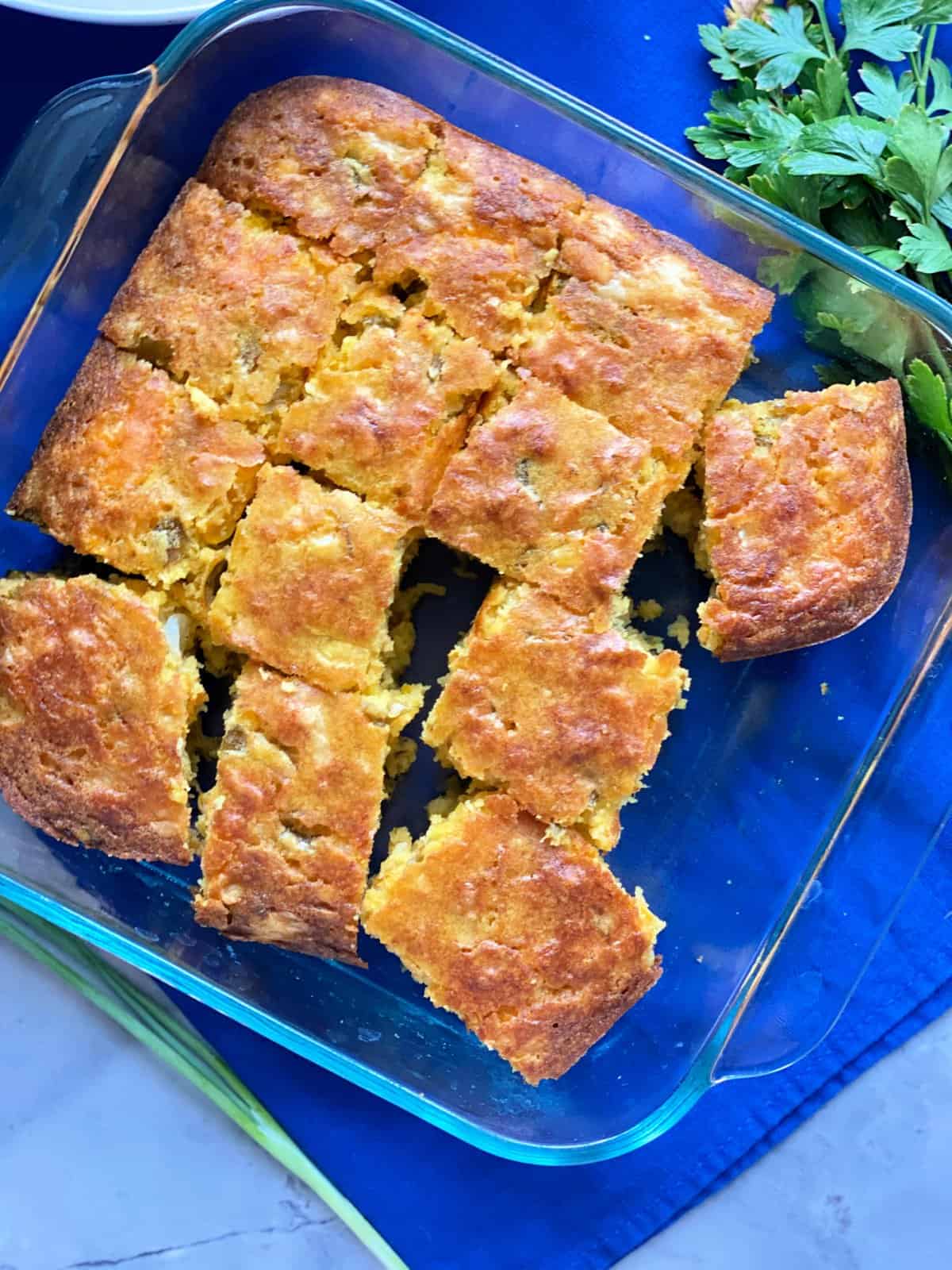 top view shot of thirteen slices of cornbread in square glass baking dish