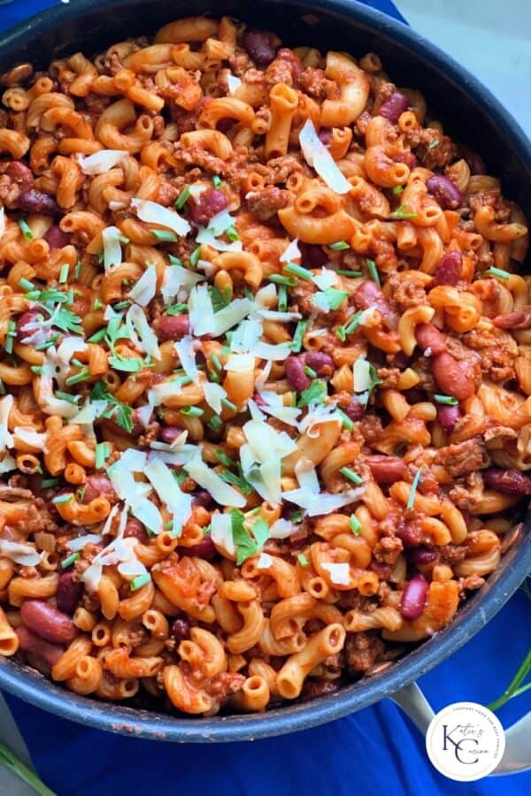 Chili pasta in skillet topped with shredded cheese