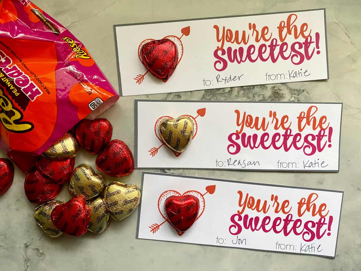 Three valentine's with heart chocolate reese's on a countertop.