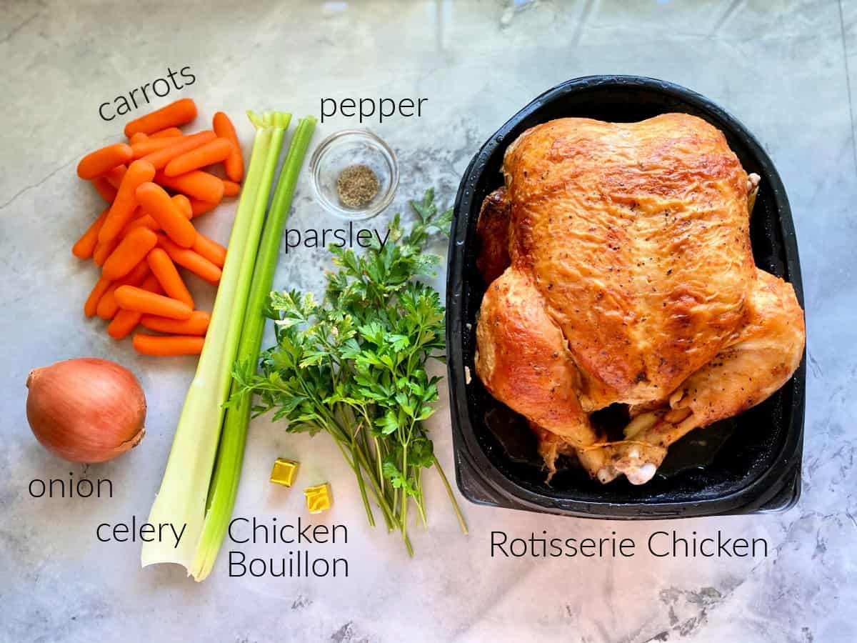 Ingredients on counter; rotisserie chicken, parsley, onion, carrots, celery, pepper, and chicke bouillon.