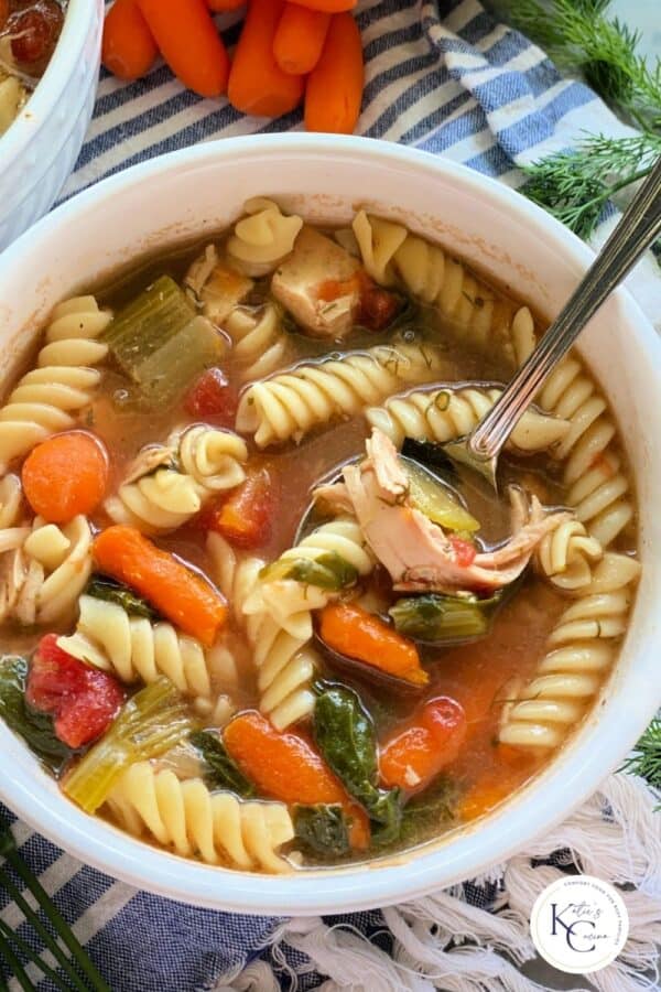 Top view shot of chicken noodle soup in white bowl with spoon