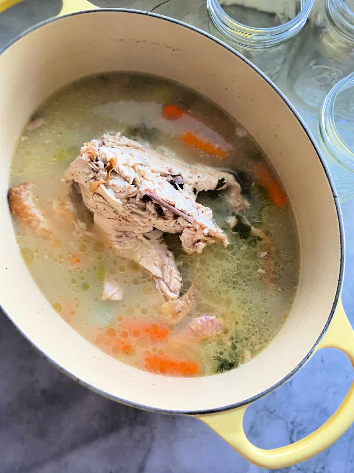Rotisserie chicken carcass in pot with broth