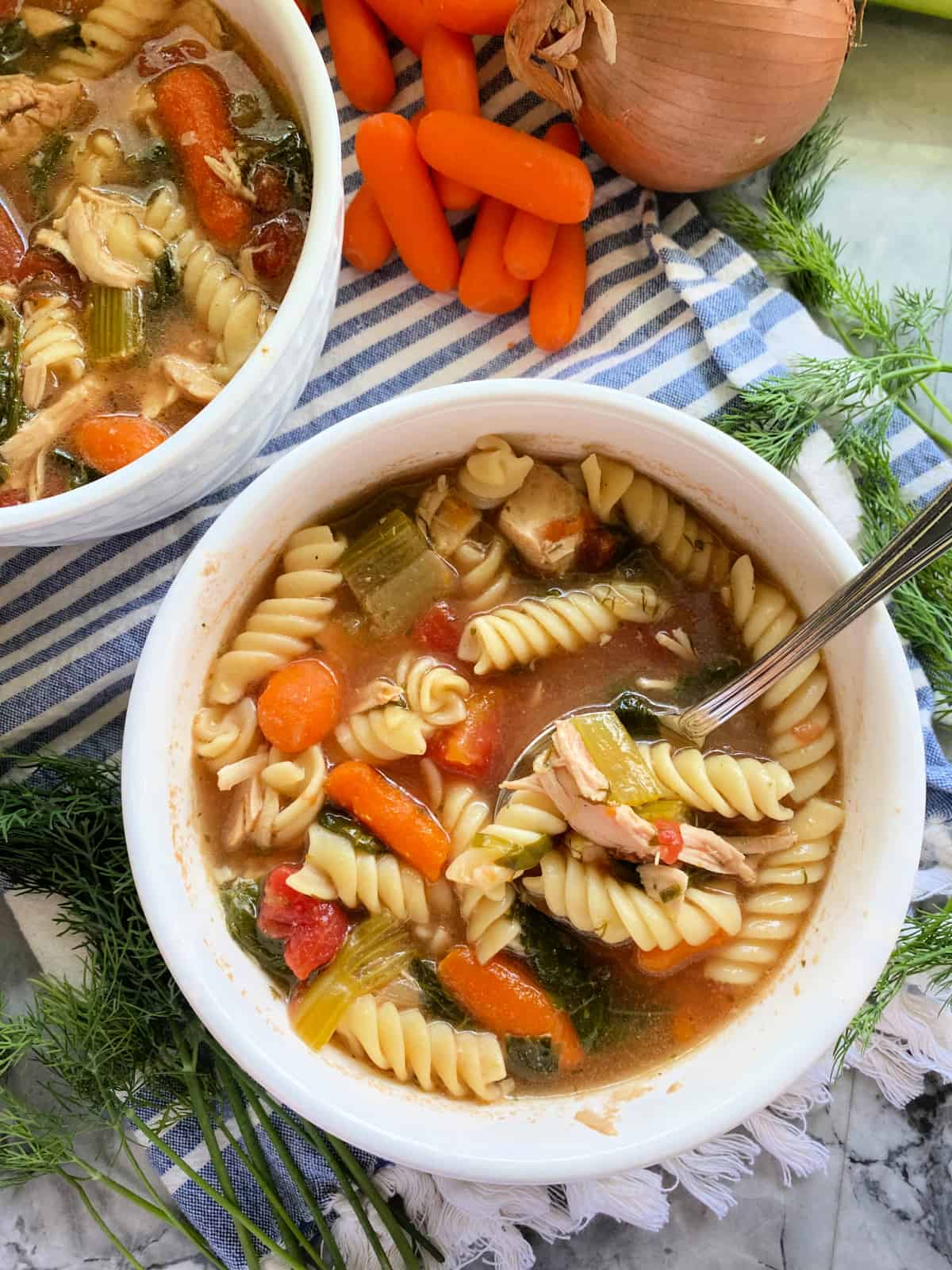 Rotisserie chicken noodle soup in two white bowl with spoon