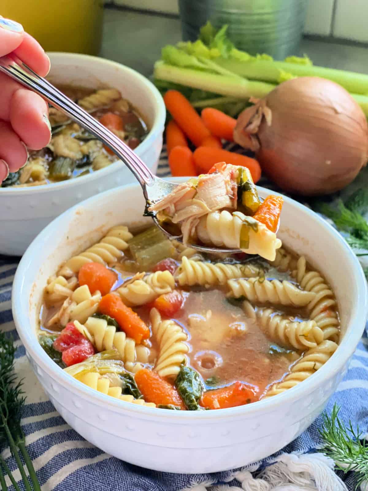 Rotisserie chicken noodle soup in white bowl with spoon