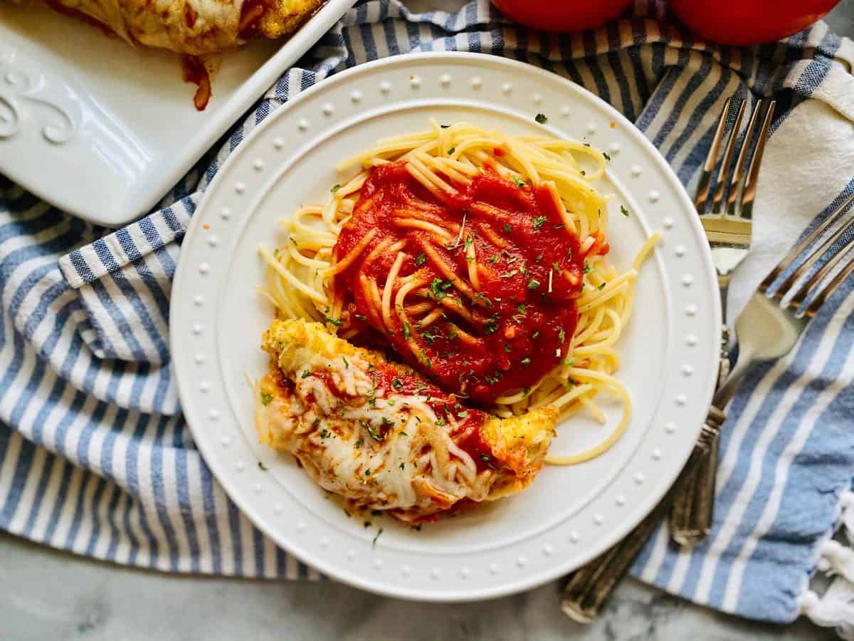 Top view shot of chicken parmesan and pasta on a white plate