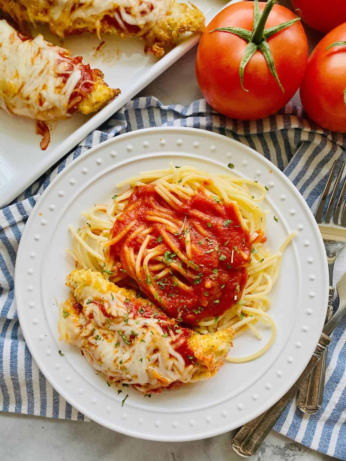 Top view shot of chicken parmesan and spaghetti on a white plate
