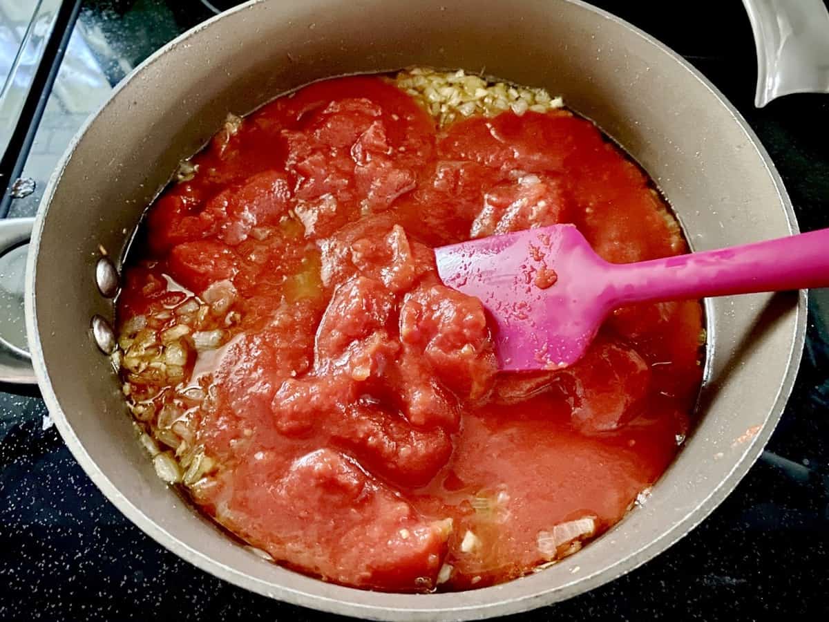 Mixing the tomato sauce with the fried aromatics in pot