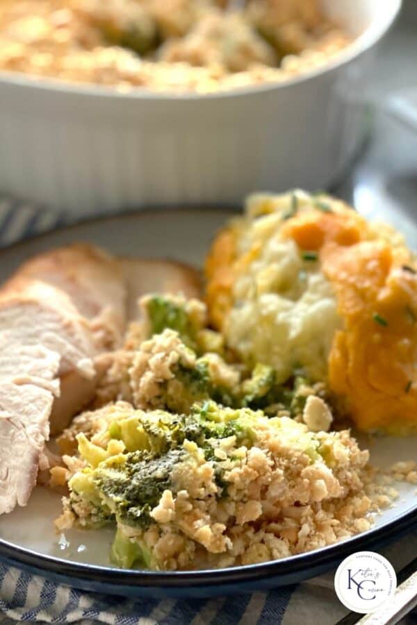 Broccoli casserole on a white plate with turkey and mashed potatoes