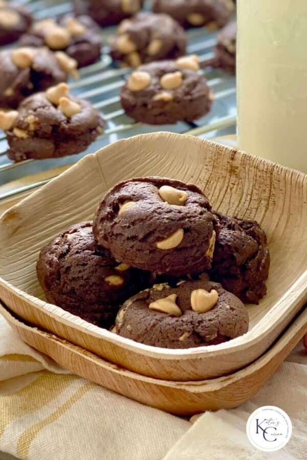 Four chocolate peanut butter chip cookies in a wooden bowl