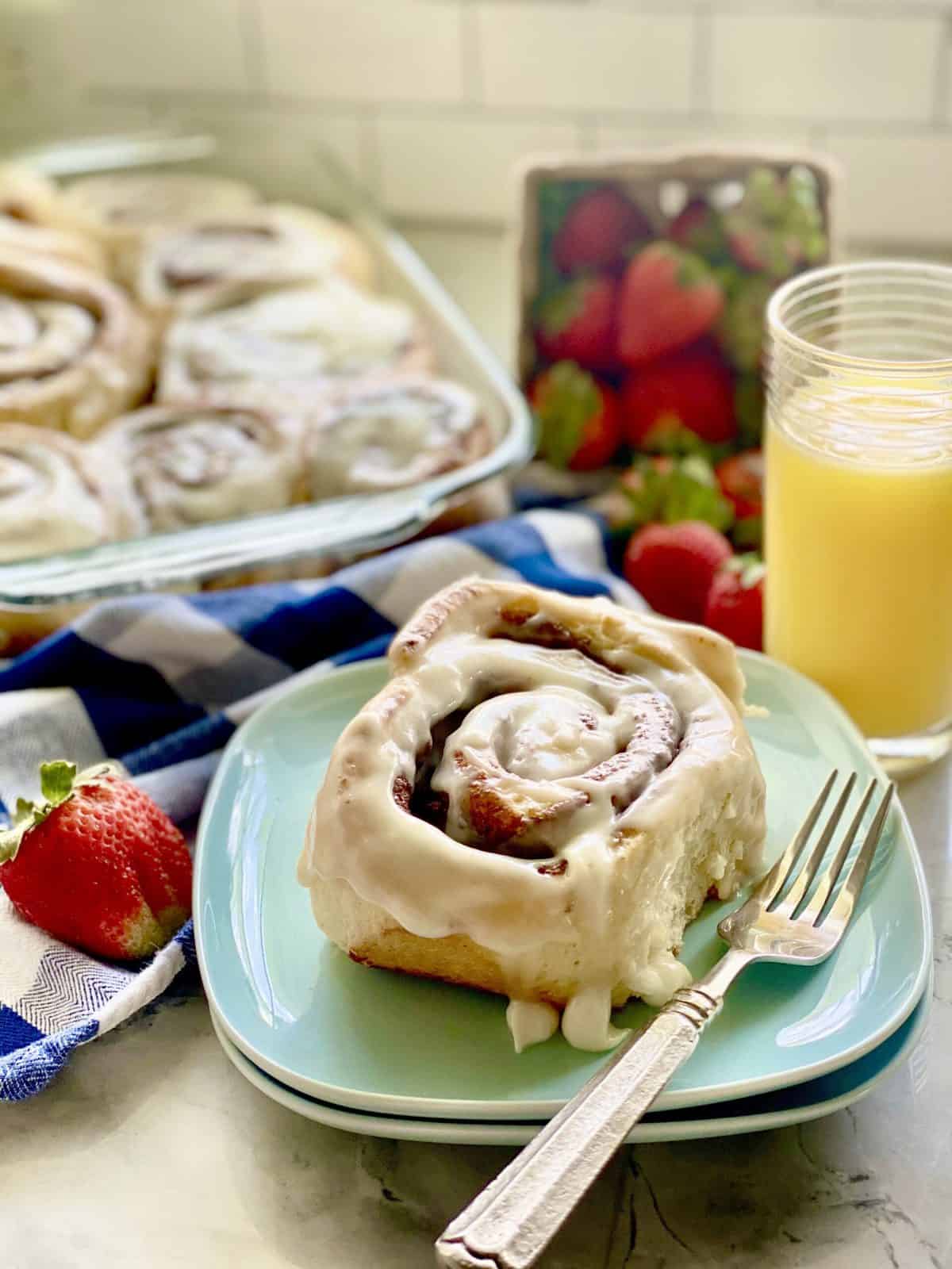 Cinnamon roll with a fork on top of blue square plates.