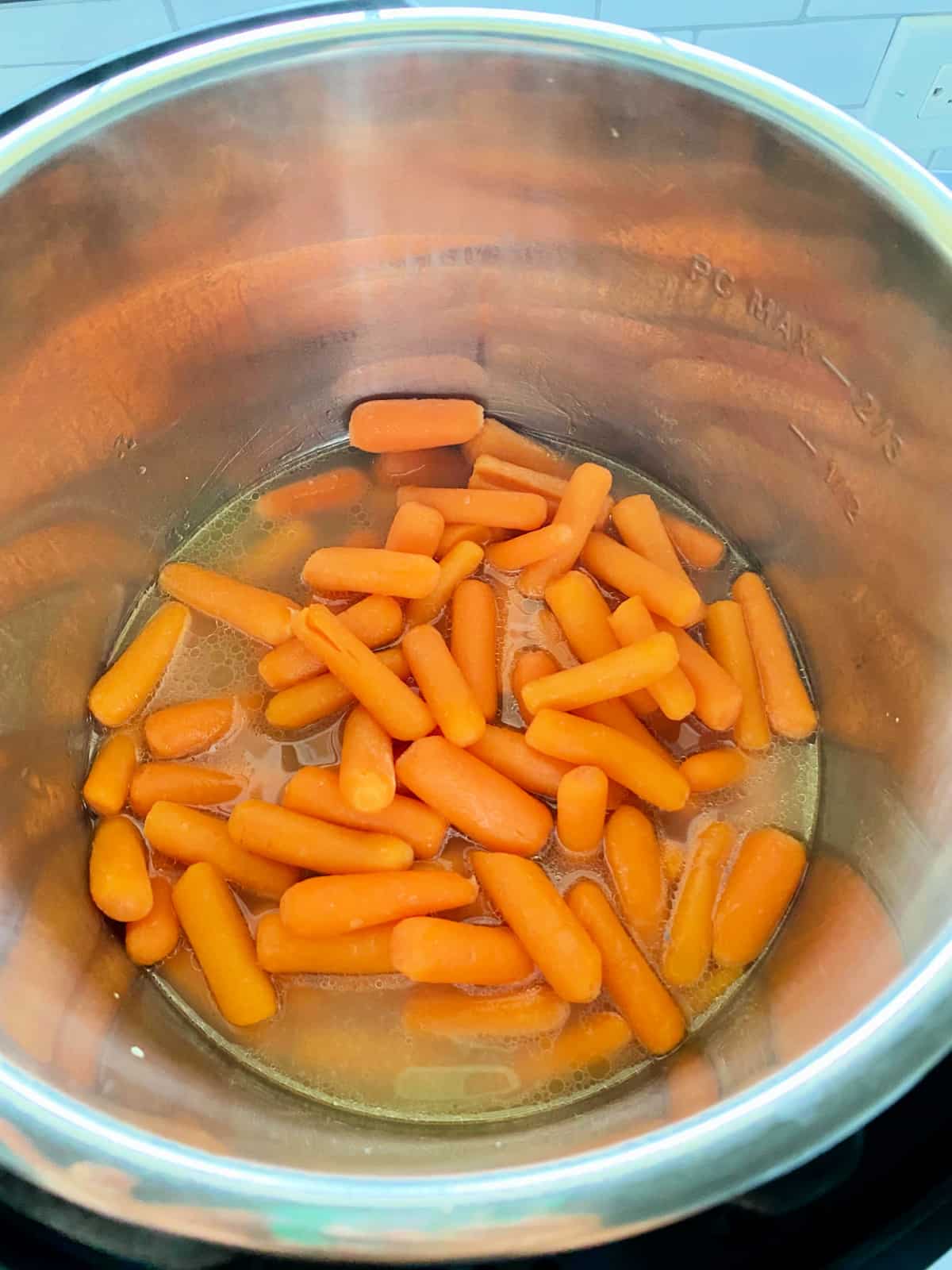 Top view of an instant pot with cooked baby carrots.
