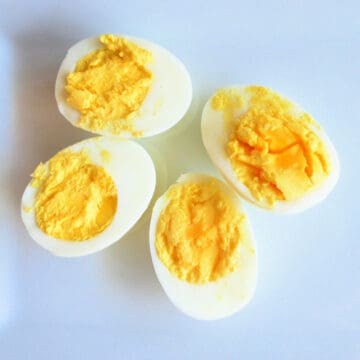 Four pieces of sliced hard boiled eggs on a white plate.