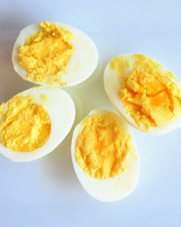 Four pieces of sliced hard boiled eggs on a white plate.