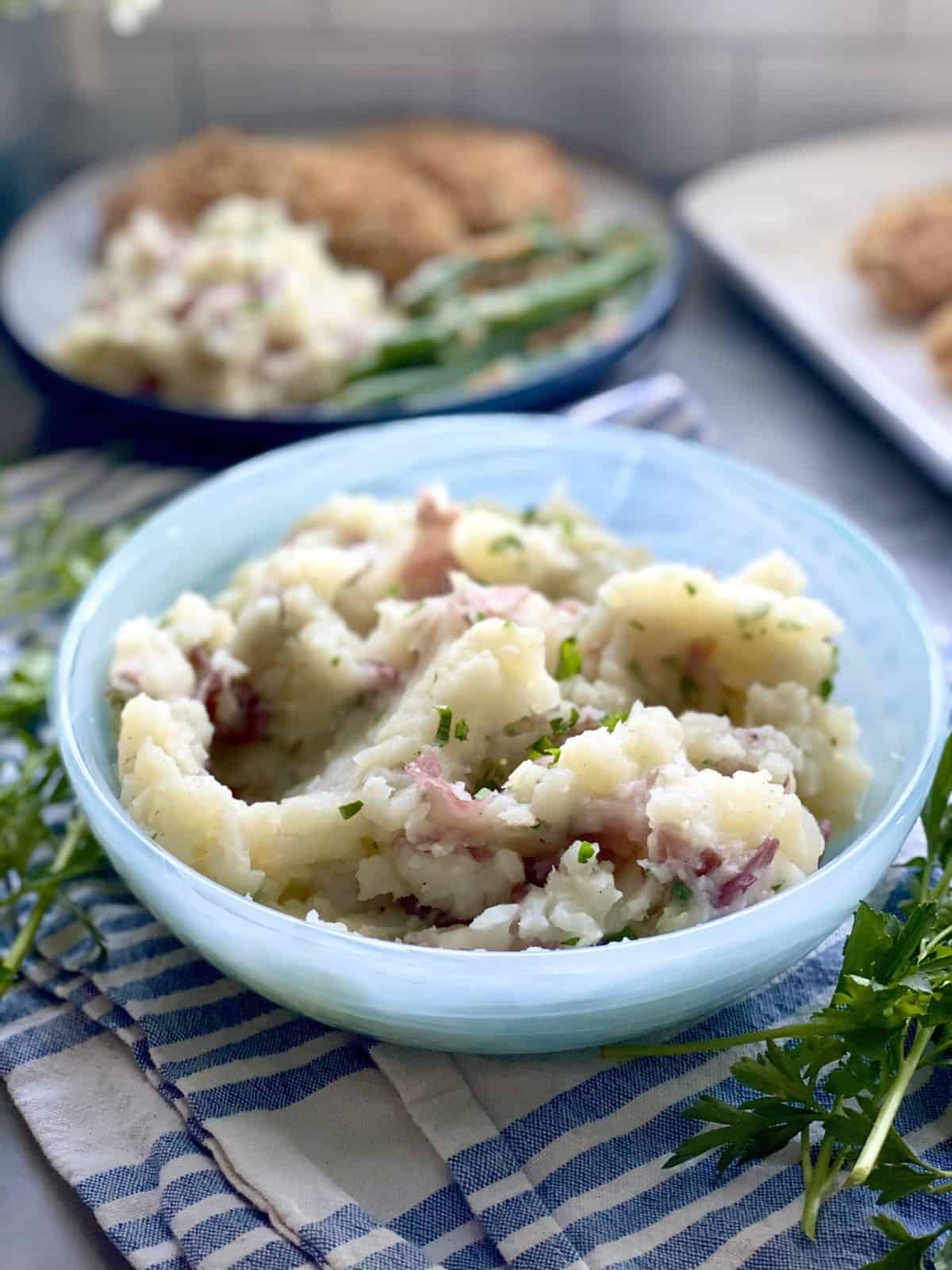 Potato and cauliflower mash in a blue serving dish over a white and blue striped towel