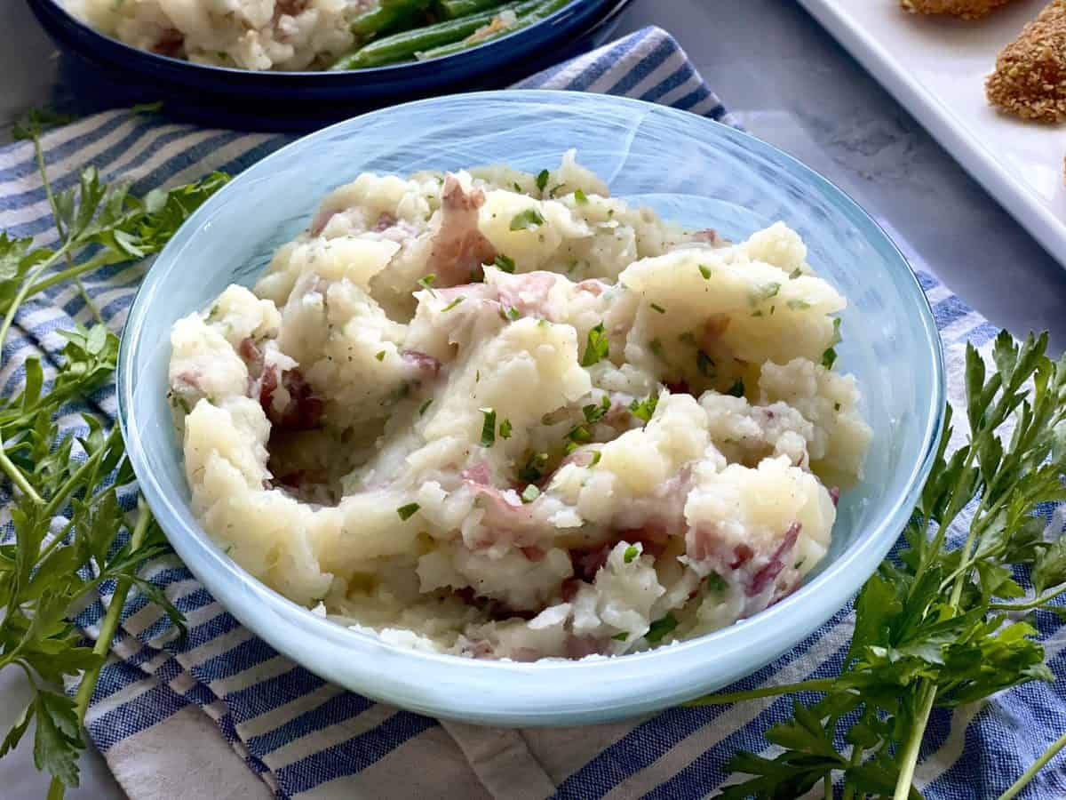 Potato and cauliflower mash in a blue serving dish over a white and blue striped towel