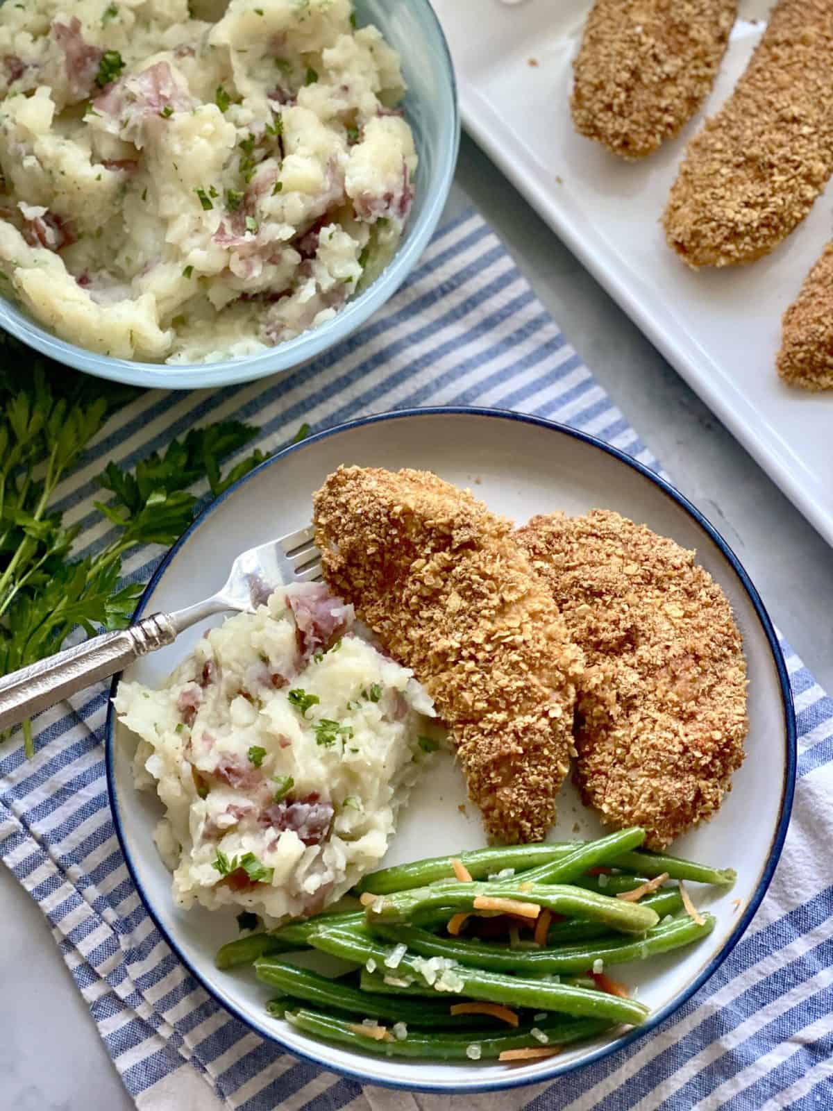 Top view of Potato and cauliflower mash on a white plate served with fried chicken and green beans