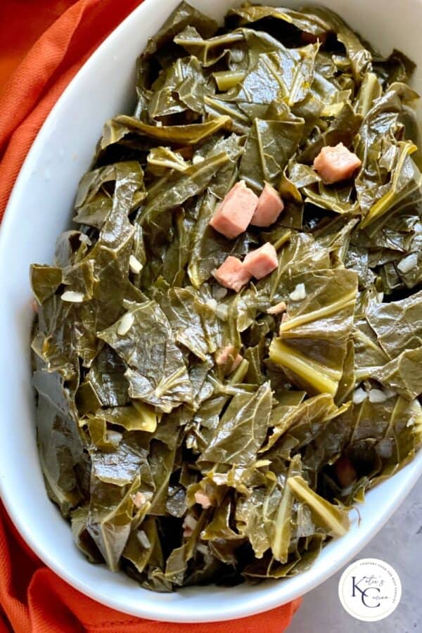 Collard greens in a white serving dish over red cloth