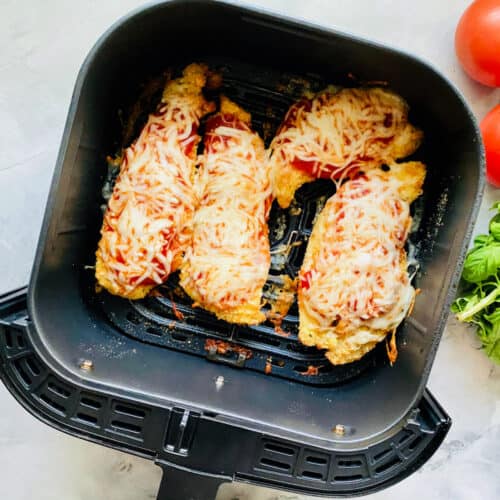 Top view of an air fryer drawer with four chicken breast.