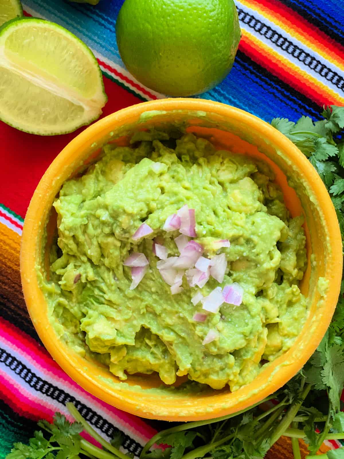 yellow bowl filled with guacamole topped with chopped onion. 