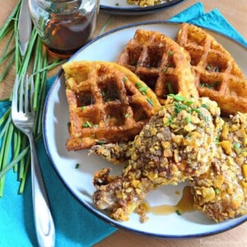 White plate with three waffles with fried chicken leg on top.