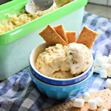 Two bowls stacked with ice cream and graham crackers sticking out of bowl.