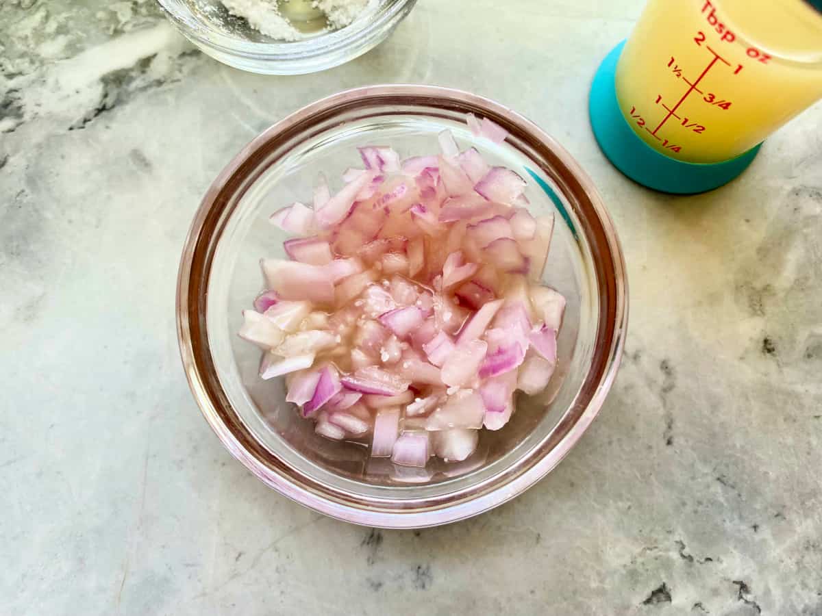 Top view of a glass bowl with chopped red onions.