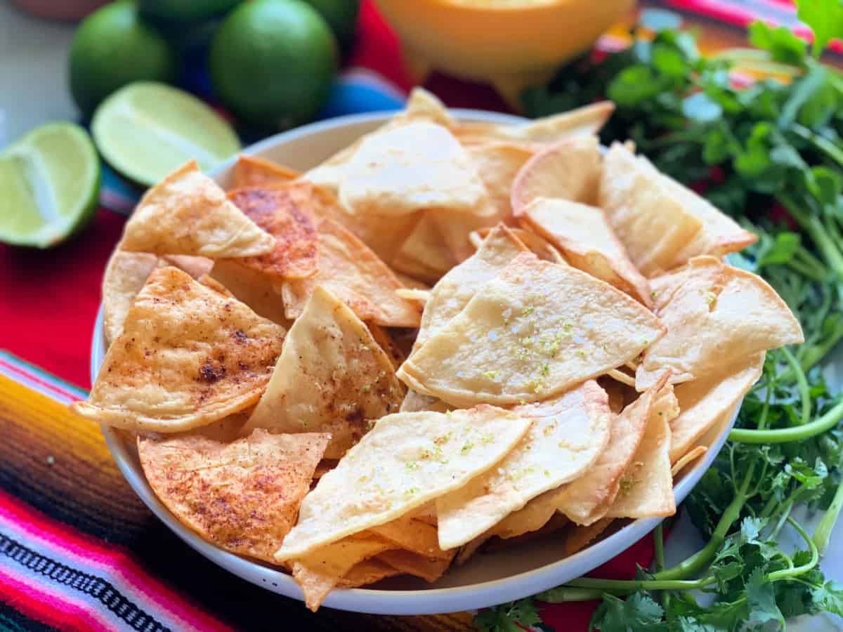 White bowl filled with tortilla chips on a striped bright color table cloth.