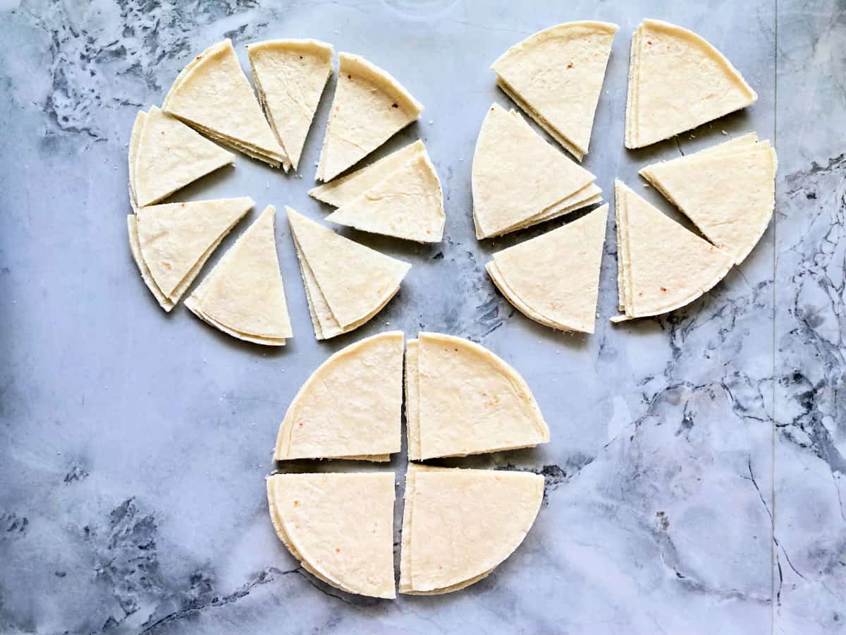 3 different circles of tortillas cut into 4, 6, and 8 pieces on a marble countertop.
