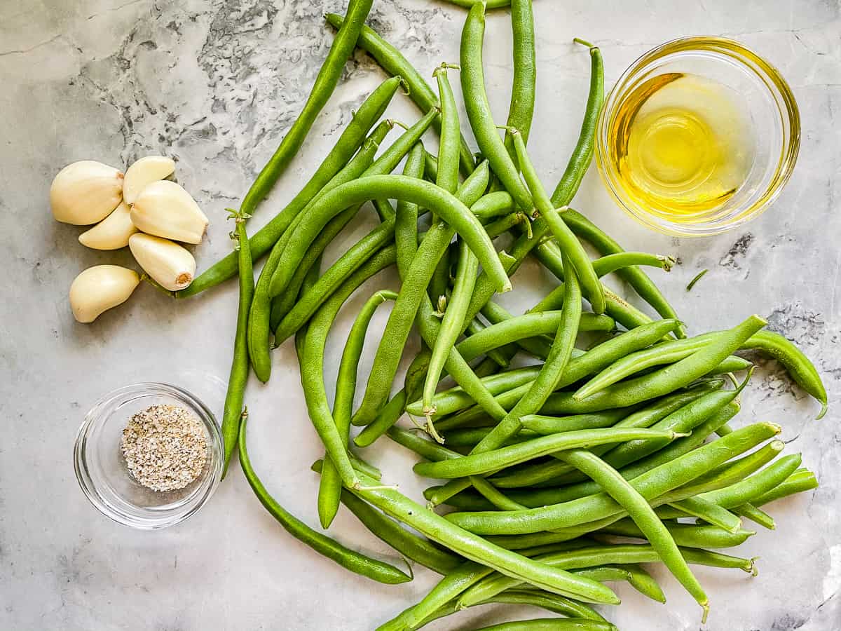 Ingredients on counter; green beans, garlic, olive oil, house seasoning.