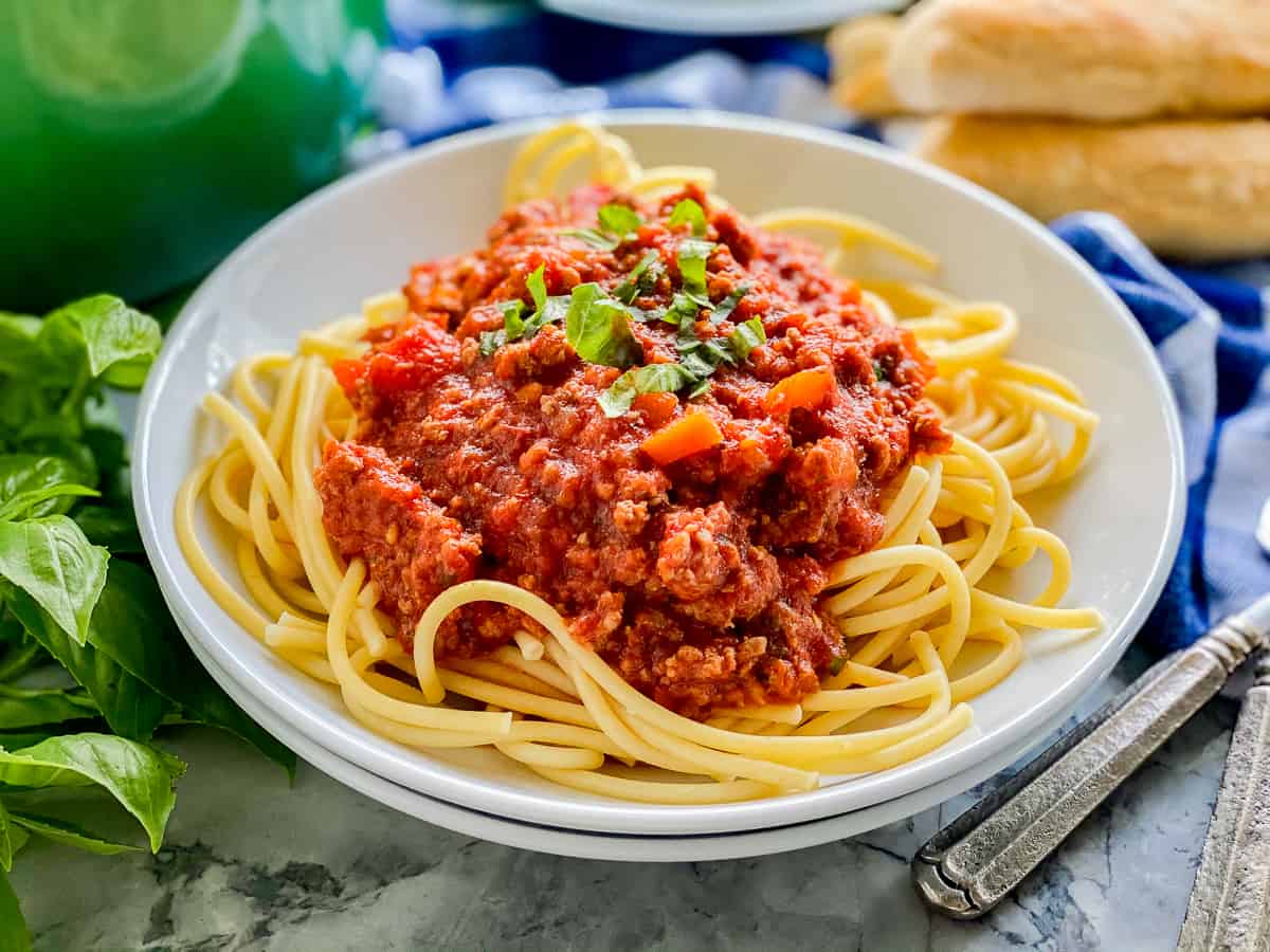 white plate with yellow spaghetti and red sauce on top.