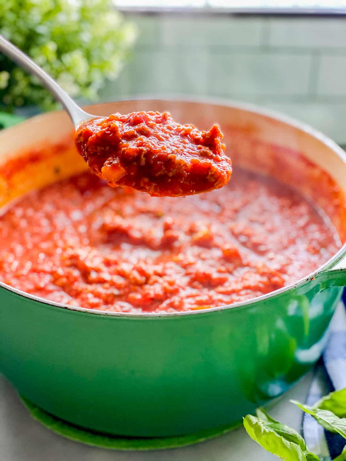 Green pot with red sauce and spoon with red sauce.