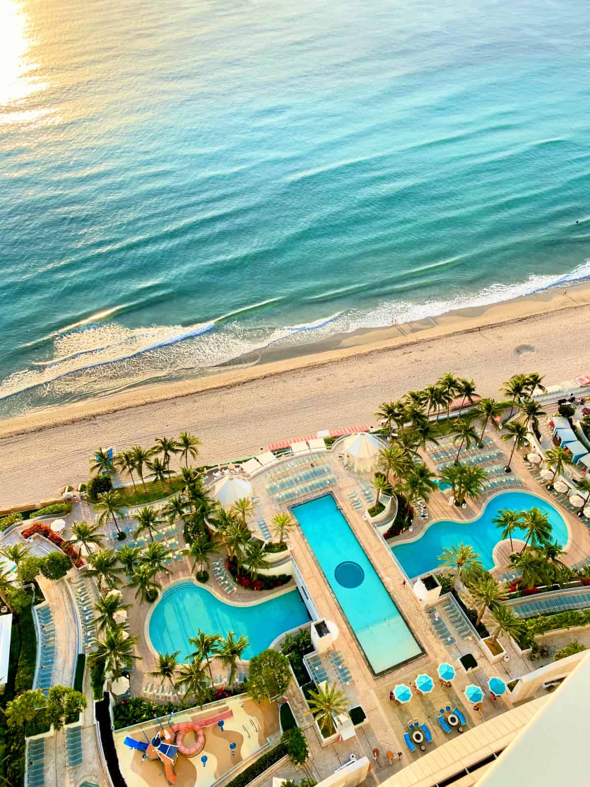 A beach and three pools with palm trees. 