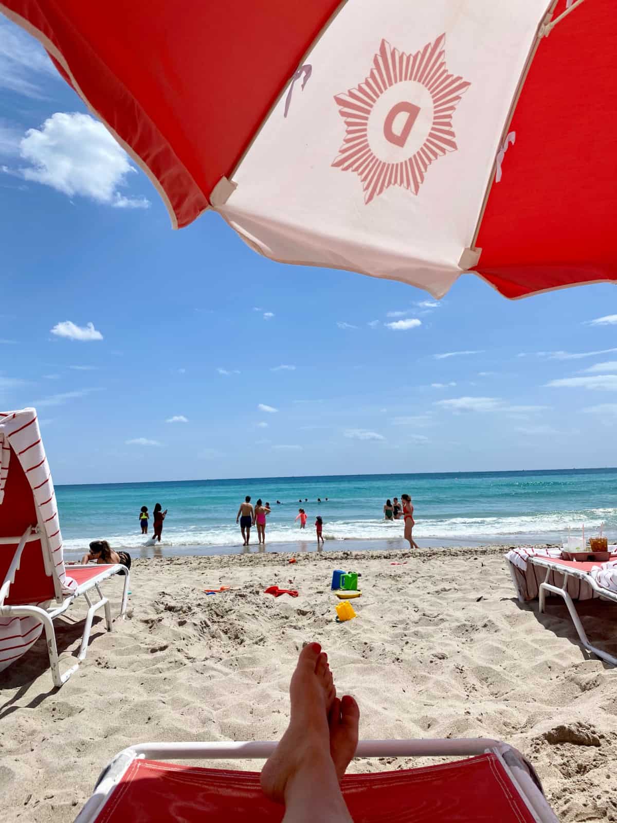 Female feet on a red lounge chair over looking the beach. 