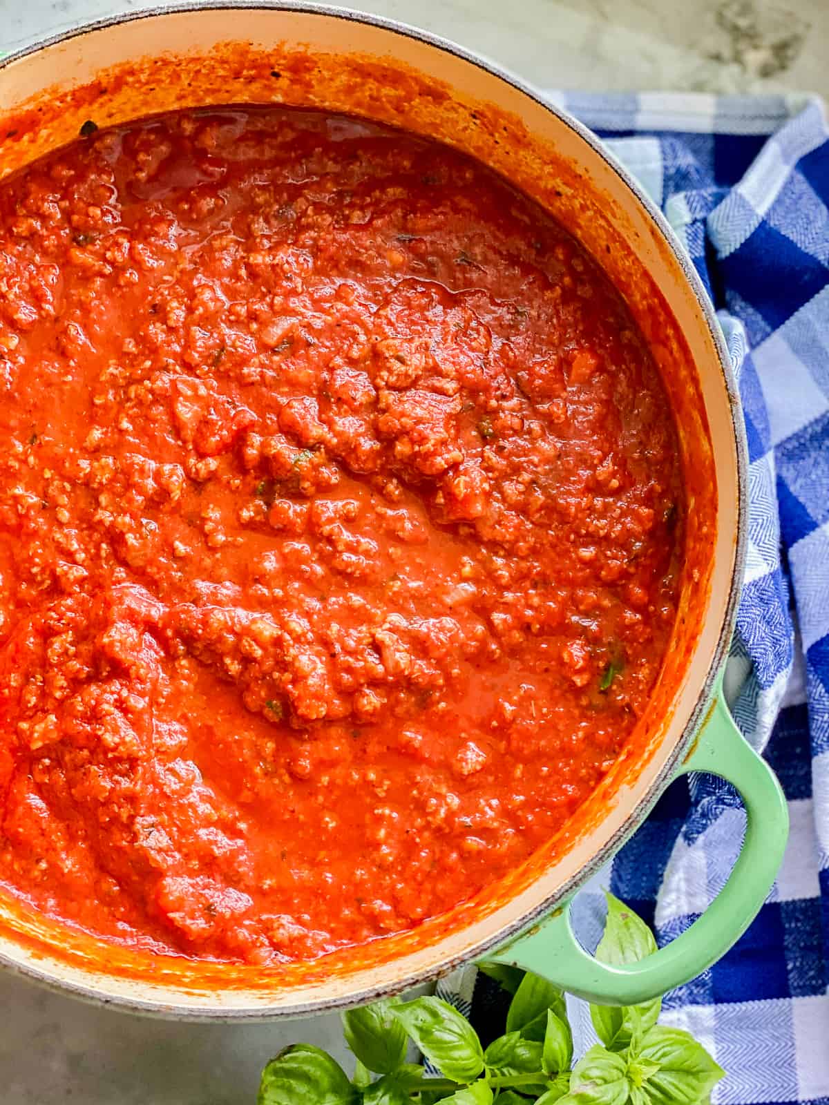 white bowl with green handle with red sauce inside.