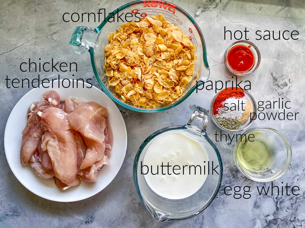 ingredients on counter; cornflakes, chicken tenderloins, buttermilk, hot sauce, seasonings, and egg whites