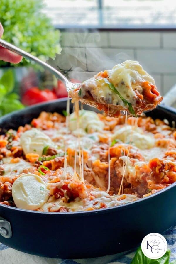 Spoon pulling lasagna out of a skillet with logo on the right corner.