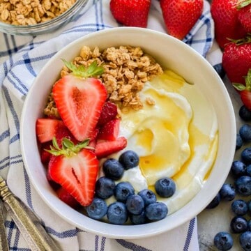 White bowl filled with yogurt, fruit, and granola.