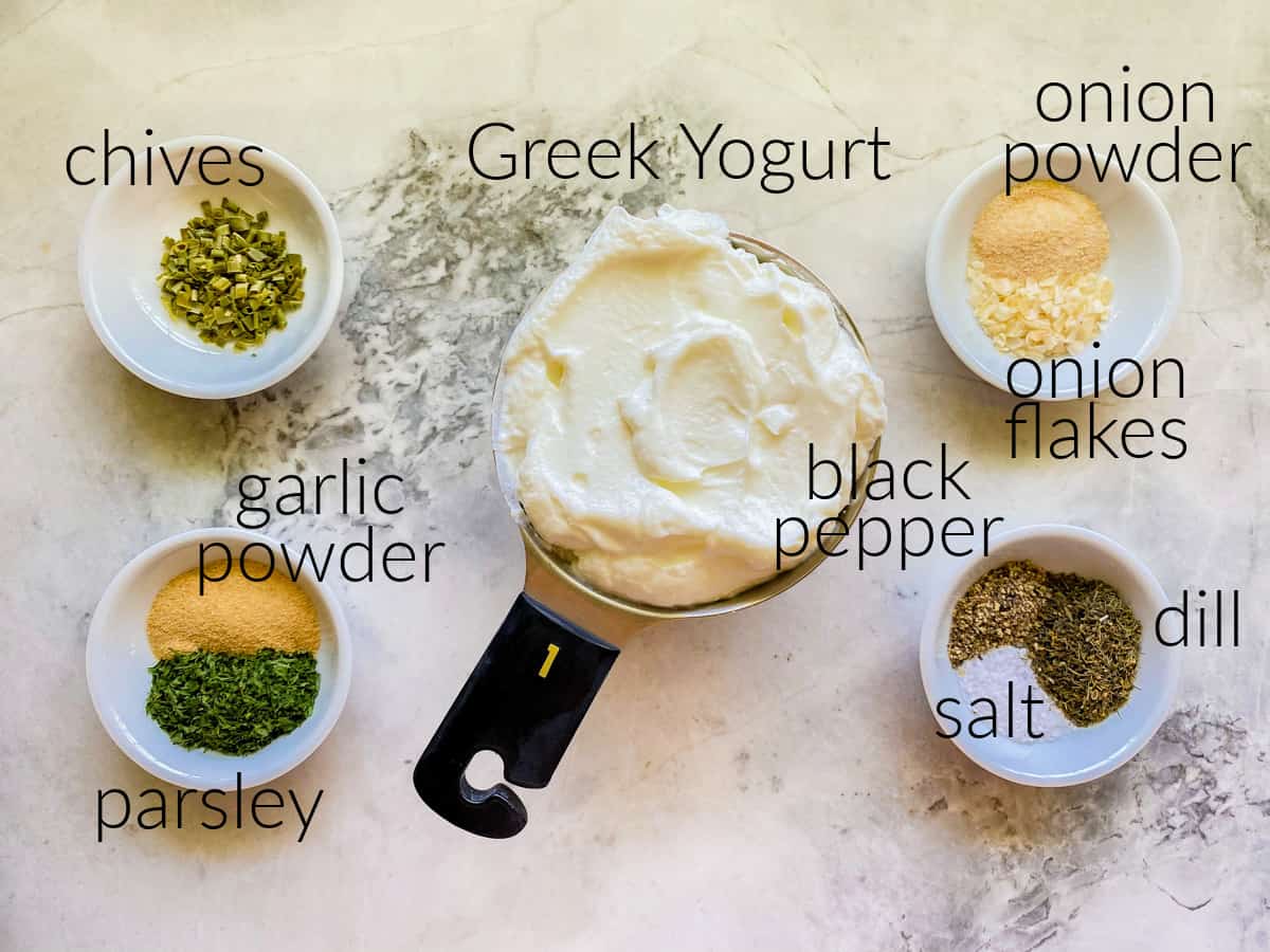 Ingredients on counter: chives, garlic powder, parsley, greek yogurt, onion powder, onion flakes, pepper, salt, and dill.