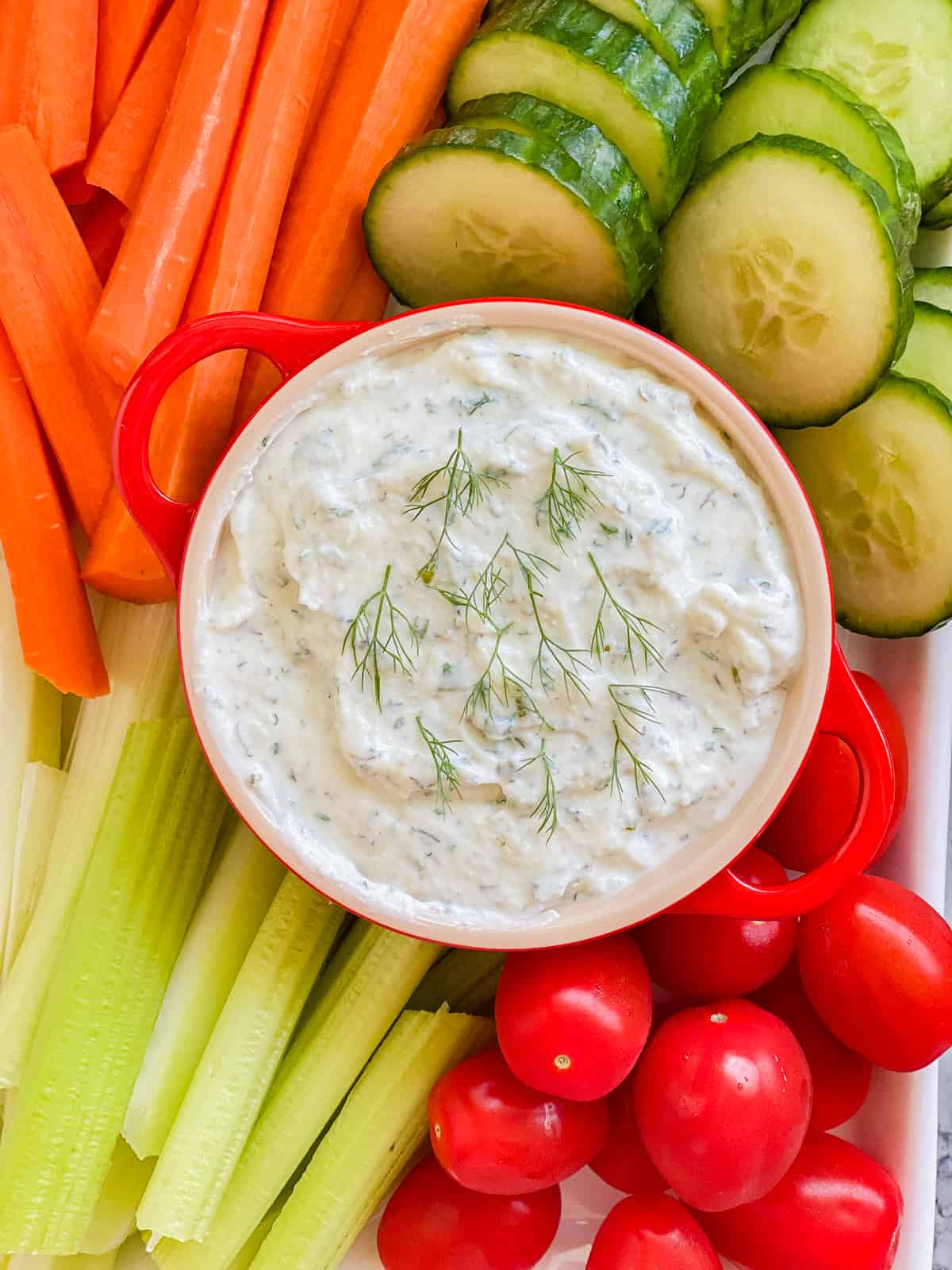 White dip with carrots, celery, cucumbers, and tomatoes.