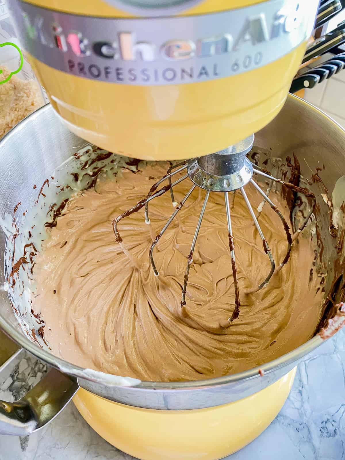 Yellow KitchenAid mixer with a balloon whisk with chocolate mouuse.