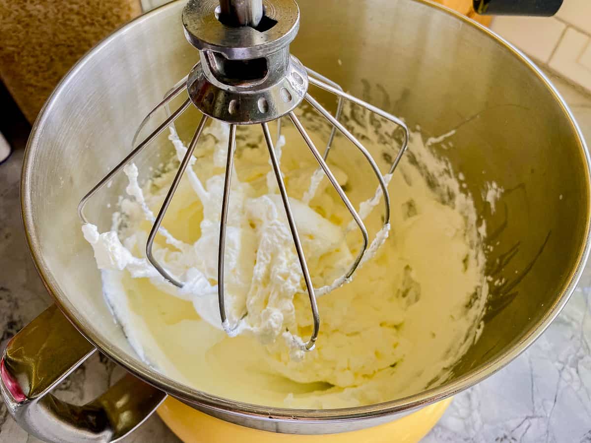 Silver bowl with balloon whisk with whipped cream.