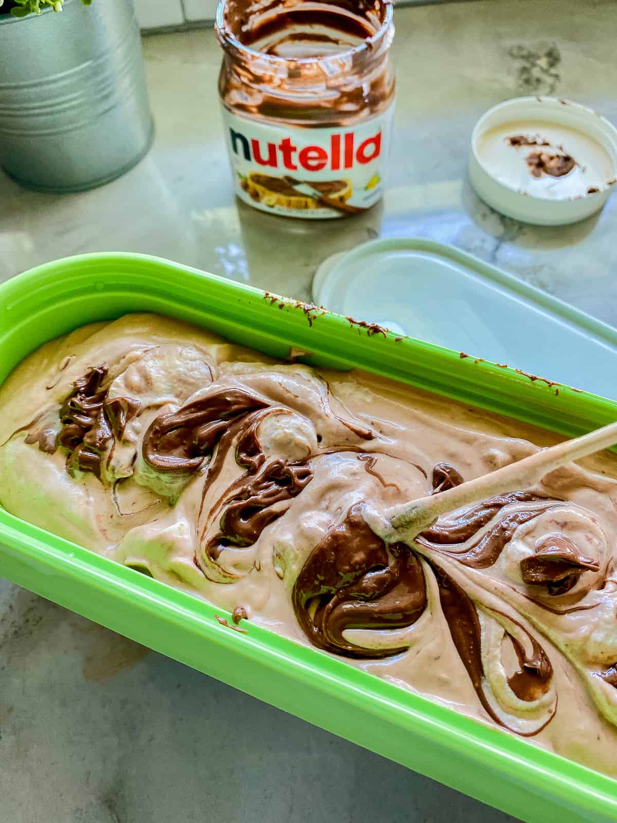 Green container with chocolate ice cream swirled in the container.